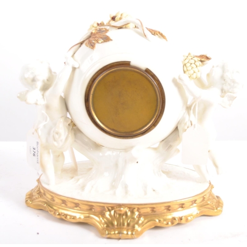 626 - A late 19th century porcelain mantel clock, decorated with cherubs eating grapes on a gilded base. T... 