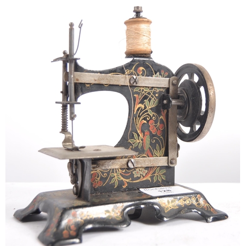 633 - A 19th Century miniature painted tin childs sewing machine along with a small cast iron iron and tri... 