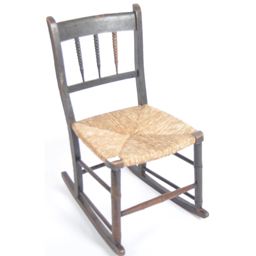 97 - A 19th Century oak child's rocking chair with spindle back having a woven grass seat raised on block... 