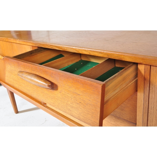 694 - A retro vintage mid 20th century teak sideboard credenza having a central bank of three drawers flan... 