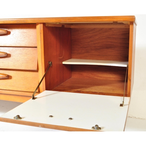 694 - A retro vintage mid 20th century teak sideboard credenza having a central bank of three drawers flan... 