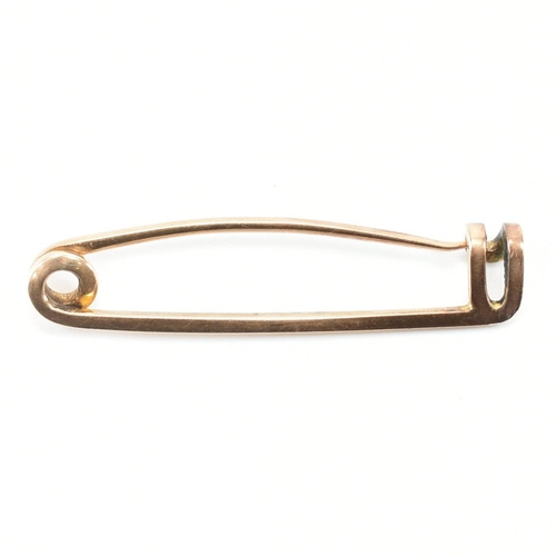 A gold safety pin brooch. The brooch having a hinge pin with a c clasp