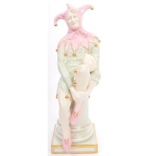 189 - A Royal Doulton table top porcelain china figurine of 'The Jester'. HN3922. In a seated position on ... 