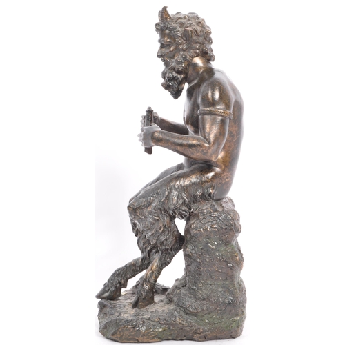 240 - A cast faux bronze classical figurine sculptural ornament in the from of a faun / satyr holding a se... 