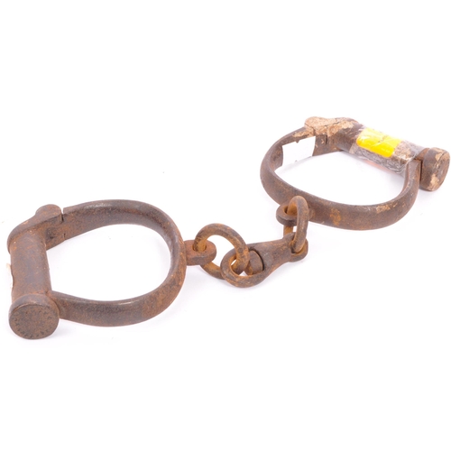 250 - An early 19th century pair of cast iron handcuffs. Stamped Hiatt 3 / 130, M&C 1916. Probably Police ... 