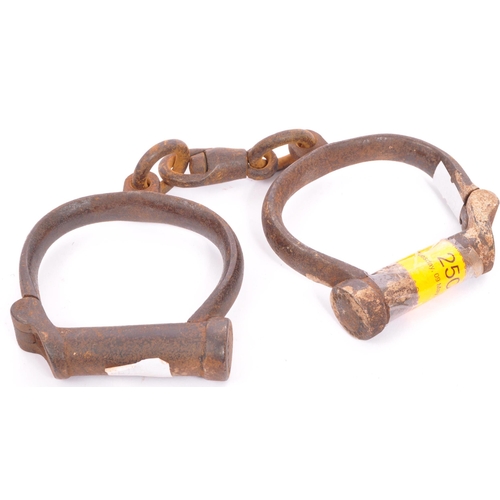 250 - An early 19th century pair of cast iron handcuffs. Stamped Hiatt 3 / 130, M&C 1916. Probably Police ... 