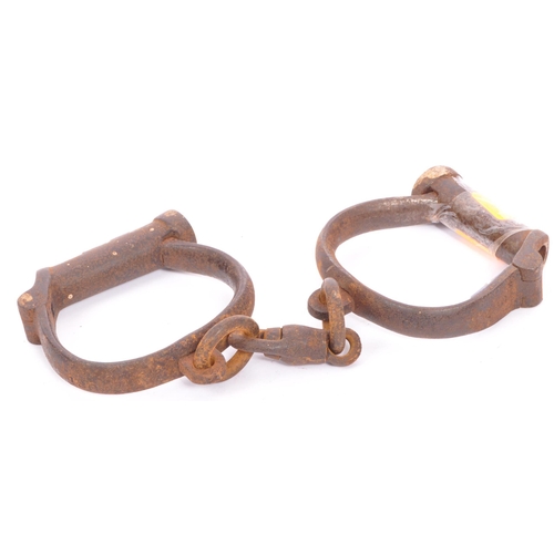 250 - An early 19th century pair of cast iron handcuffs. Stamped Hiatt 3 / 130, M&C 1916. Probably Police ... 