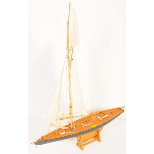 257 - A 20th century wooden scratch built pond yacht model boat with twin sail and accompanying stand.