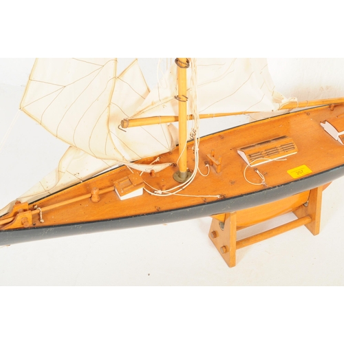 257 - A 20th century wooden scratch built pond yacht model boat with twin sail and accompanying stand.