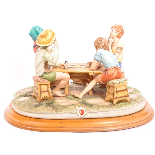 30 - A large Capodimonte group 'The Cheaters', by Bruno Merli, depicting four boys playing cards, on stai... 