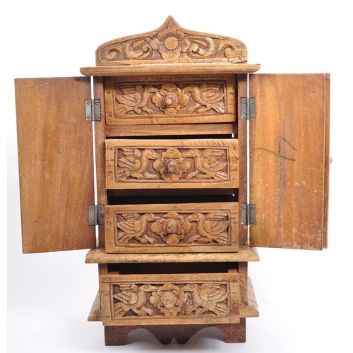 324 - A 20th century Indian folk hardwood carved jewellery cabinet. The chest having hand carved with bird... 