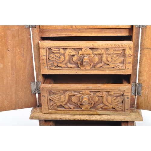 324 - A 20th century Indian folk hardwood carved jewellery cabinet. The chest having hand carved with bird... 