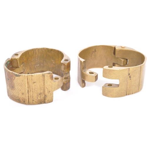 332 - A collection of 19th century brass items. Including; slave trade handcuffs / shackles, with a small ... 