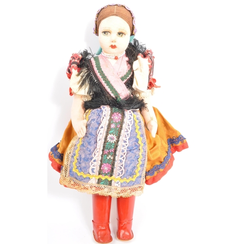 336 - Two vintage dolls comprising a European folk inspired cloth body doll with painted face wearing a tr... 