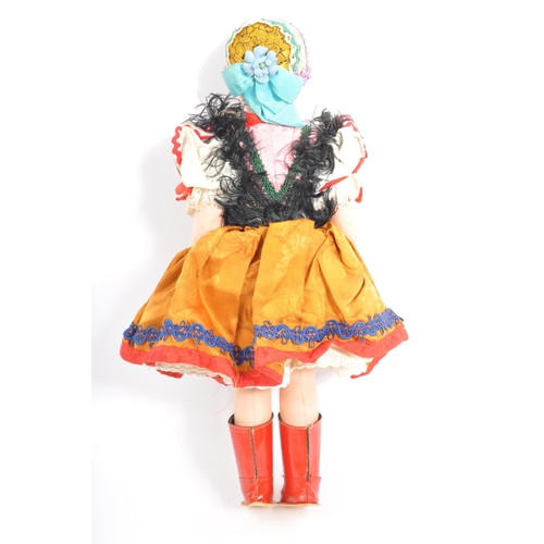 336 - Two vintage dolls comprising a European folk inspired cloth body doll with painted face wearing a tr... 