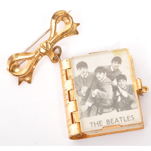 355 - A vintage 20th century The Beatles pin badge brooch. In the form of a book with concertina photos of... 