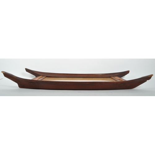 269 - A 20th century Polynesian carved wooden tray. The tray having inlaid mother of pearl and paddles car... 