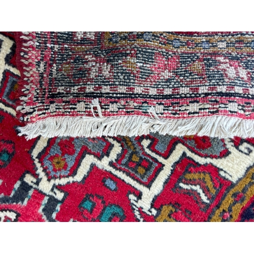 64 - An early 20th century North West Persian Islamic Heriz hand woven floor carpet runner rug having a c... 