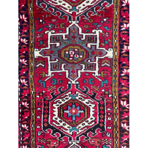 64 - An early 20th century North West Persian Islamic Heriz hand woven floor carpet runner rug having a c... 