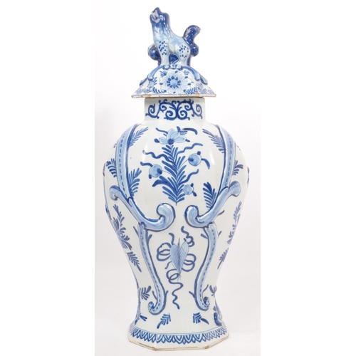 122 - An early 20th century earthenware urn / lidded vase, with moulded lion / dog mounted atop, seated up... 