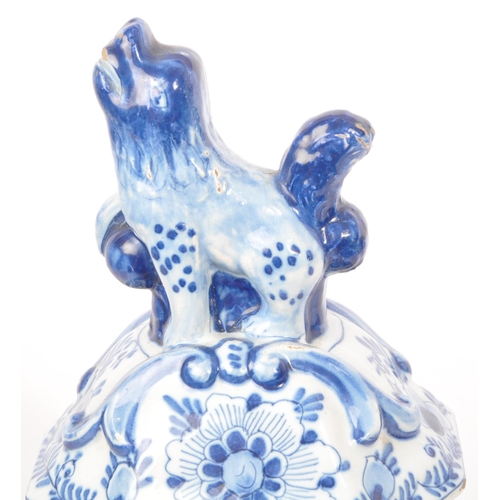 122 - An early 20th century earthenware urn / lidded vase, with moulded lion / dog mounted atop, seated up... 