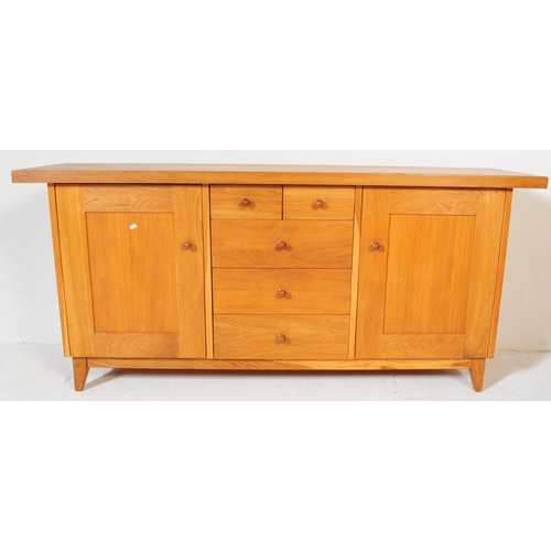 557 - A contemporary Oak Furniture Land style sideboard credenza. Of rectangular form with flared top, rai... 
