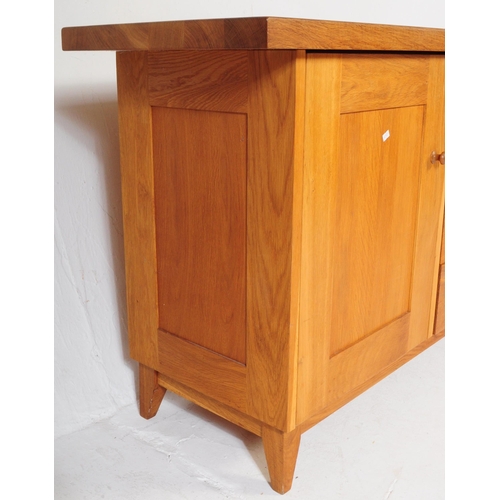 557 - A contemporary Oak Furniture Land style sideboard credenza. Of rectangular form with flared top, rai... 