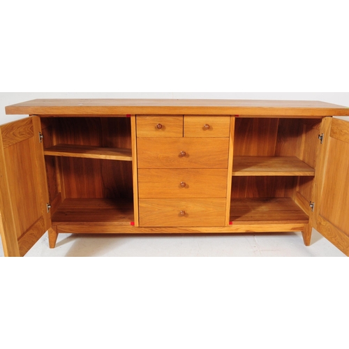 557 - A contemporary Oak Furniture Land style sideboard credenza. Of rectangular form with flared top, rai... 