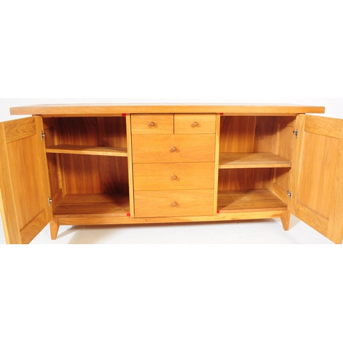 557 - A contemporary Oak Furniture Land style sideboard credenza. Of rectangular form with flared top, rai... 