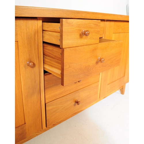 557 - A contemporary Oak Furniture Land style sideboard credenza. Of rectangular form with flared top, rai... 