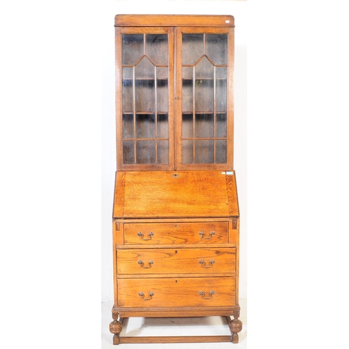 1003 - A 1920s George V oak bureau bookcase. The bureau being raised on shaped supports having a fall front... 