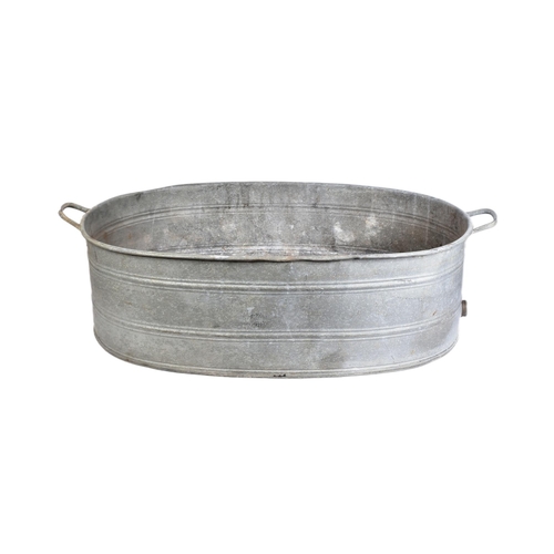 119 - An early 20th century large oval galvanised tin bath. Of oval form, with handles to either side and ... 