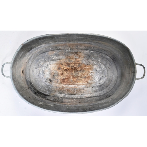 119 - An early 20th century large oval galvanised tin bath. Of oval form, with handles to either side and ... 