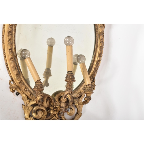 14 - An 18th century George III oval gilt girandole mirror of Rococo taste. The frame of giltwood and ges... 