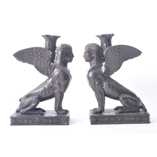 196 - A pair of 20th century bronze patinated Egyptian revival Sphinx candlestick holders. The sphinxes ea... 