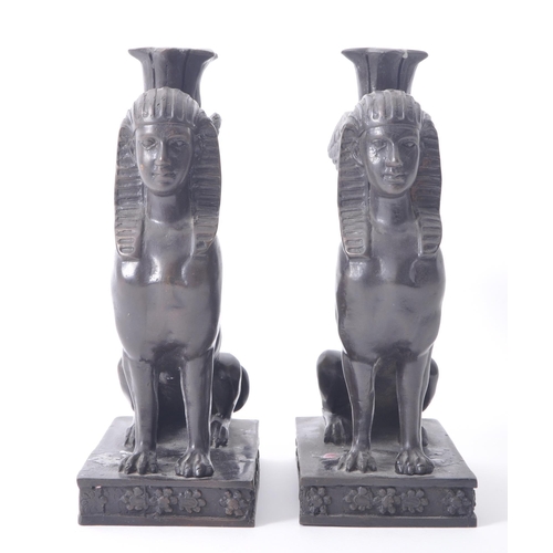 196 - A pair of 20th century bronze patinated Egyptian revival Sphinx candlestick holders. The sphinxes ea... 