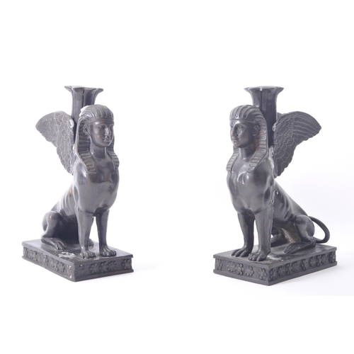 196 - A pair of 20th century bronze patinated Egyptian revival Sphinx candlestick holders. The sphinxes ea... 