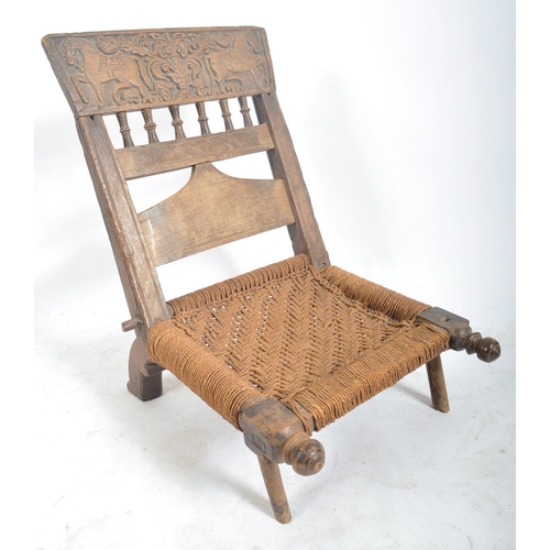 216 - A set of four early 20th century carved wood Indian Pida Rajasthani low chairs. Each having a carved... 