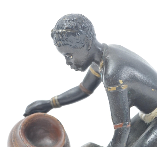 426 - An early 20th century cold painted bronze figure of a kneeling African tribal woman filling a pot wi... 