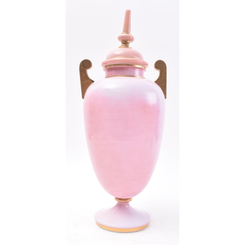 647 - A late 19th Century French opaline pink glass urn. The urn having a finial topped cover with bulbous... 