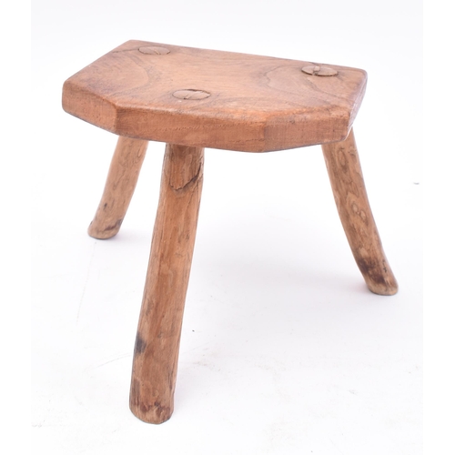 657 - A 19th century miniature elm stool. The stool having a shaped top supported by three elm supports. M... 