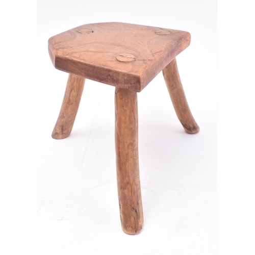 657 - A 19th century miniature elm stool. The stool having a shaped top supported by three elm supports. M... 