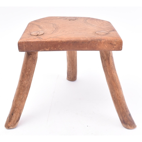 657 - A 19th century miniature elm stool. The stool having a shaped top supported by three elm supports. M... 