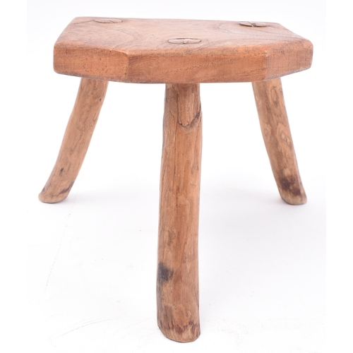 657 - A 19th century miniature elm stool. The stool having a shaped top supported by three elm supports. M... 