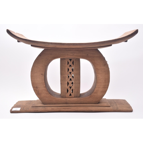 77 - An early 20th century African Ashanti carved hardwood stool. The stool having a concave seat over a ... 