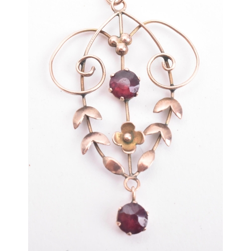 179 - An antique 9ct gold and garnet necklace pendant on a 375 marked chain. The pendant of open work scro... 