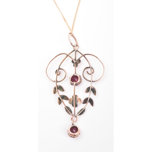 179 - An antique 9ct gold and garnet necklace pendant on a 375 marked chain. The pendant of open work scro... 