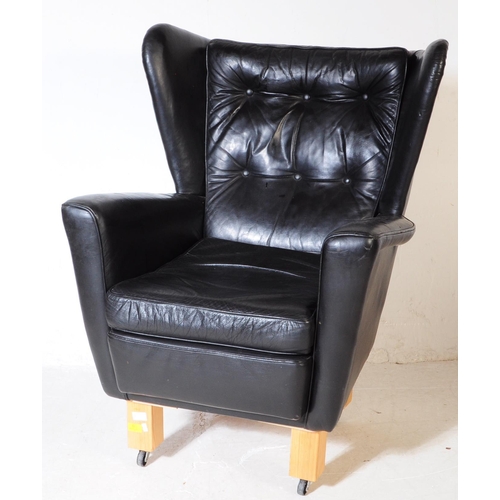 572 - G Plan - A mid 20th century G-Plan batwing black faux leatherette vinyl armchair being raised on lat... 