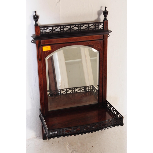 804 - An Edwardian mahogany wall hanging mirror with pierced under shelf and upper border with finial deco... 