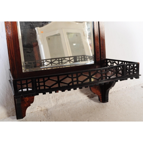 804 - An Edwardian mahogany wall hanging mirror with pierced under shelf and upper border with finial deco... 